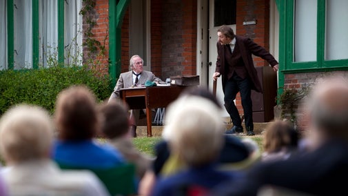 Audience watching the play at an outdoor theatre event at Shaw's Corner, Hertfordshire.